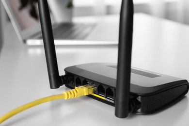 Photo of Connected cable to router on white table, closeup. Wireless internet communication