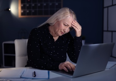 Photo of Overworked mature woman with headache in office