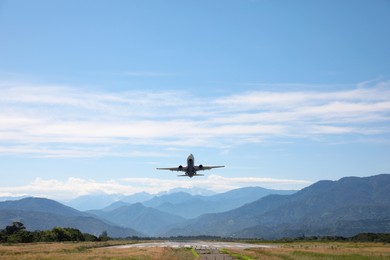 Photo of Modern white airplane landing on runway near mountains