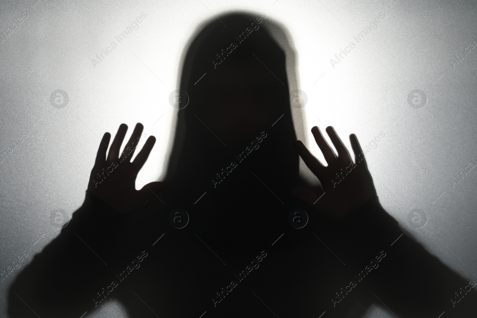 Photo of Silhouette of ghost behind glass against grey background
