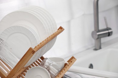 Photo of Drying rack with clean dishes in kitchen, closeup. Space for text