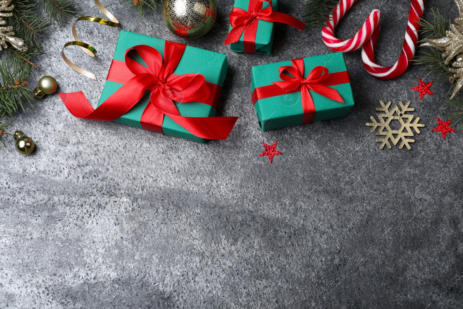 Photo of Flat lay composition with gift boxes and Christmas decorations on grey textured table, space for text