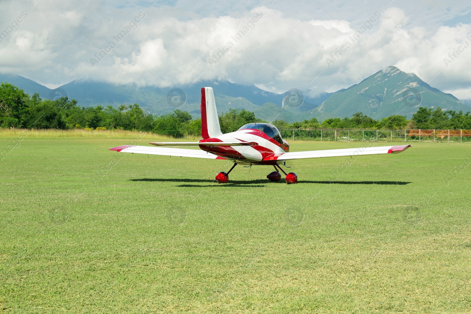 Photo of Modern airplane on green grass against mountains background