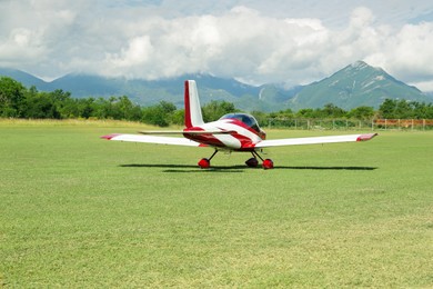 Photo of Modern airplane on green grass against mountains background