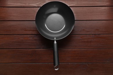 Empty iron wok on dark wooden table, top view. Chinese cookware