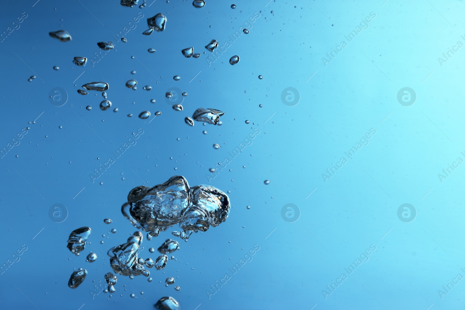 Photo of Air bubbles in water on blue background. Space for text