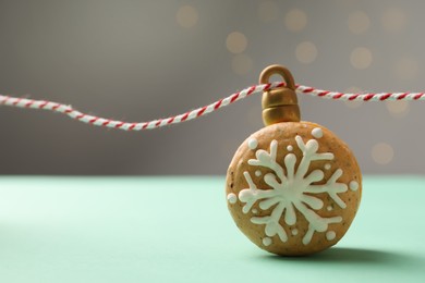 Photo of Beautifully decorated Christmas macaron with rope on turquoise table against blurred festive lights
