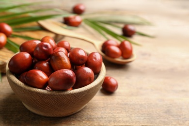 Palm oil fruits in bowl on wooden table, closeup