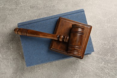 Wooden gavel, sound block and book on grey textured table, top view