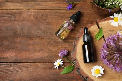 Photo of Flat lay composition with bottles of essential oils on wooden table. Space for text