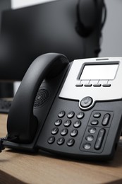Photo of Stationary phone on wooden desk in office. Hotline service