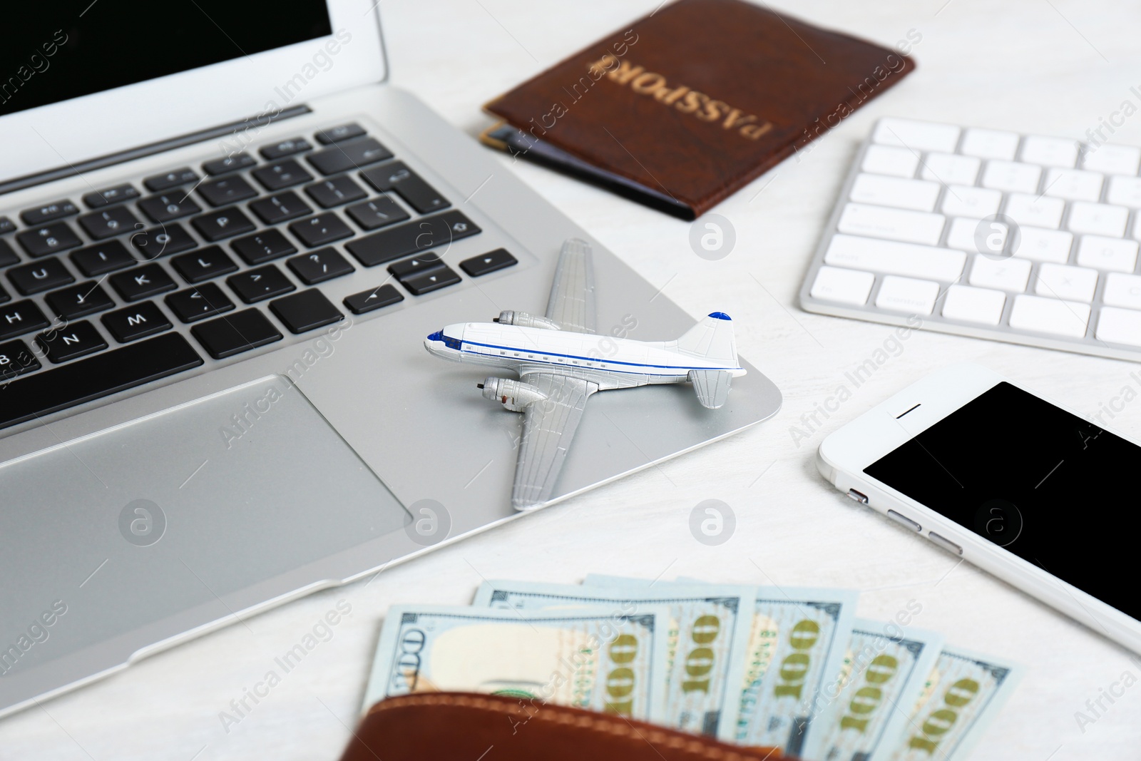 Photo of Smartphone with laptop, money and toy plane on light background. Travel agency