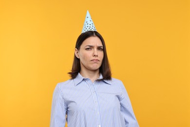 Photo of Sad young woman in party hat on yellow background