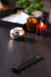 Incense stick smoldering on wooden table in room