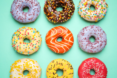 Delicious glazed donuts on turquoise background, flat lay