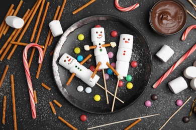 Flat lay composition with funny snowmen made of marshmallows on black table