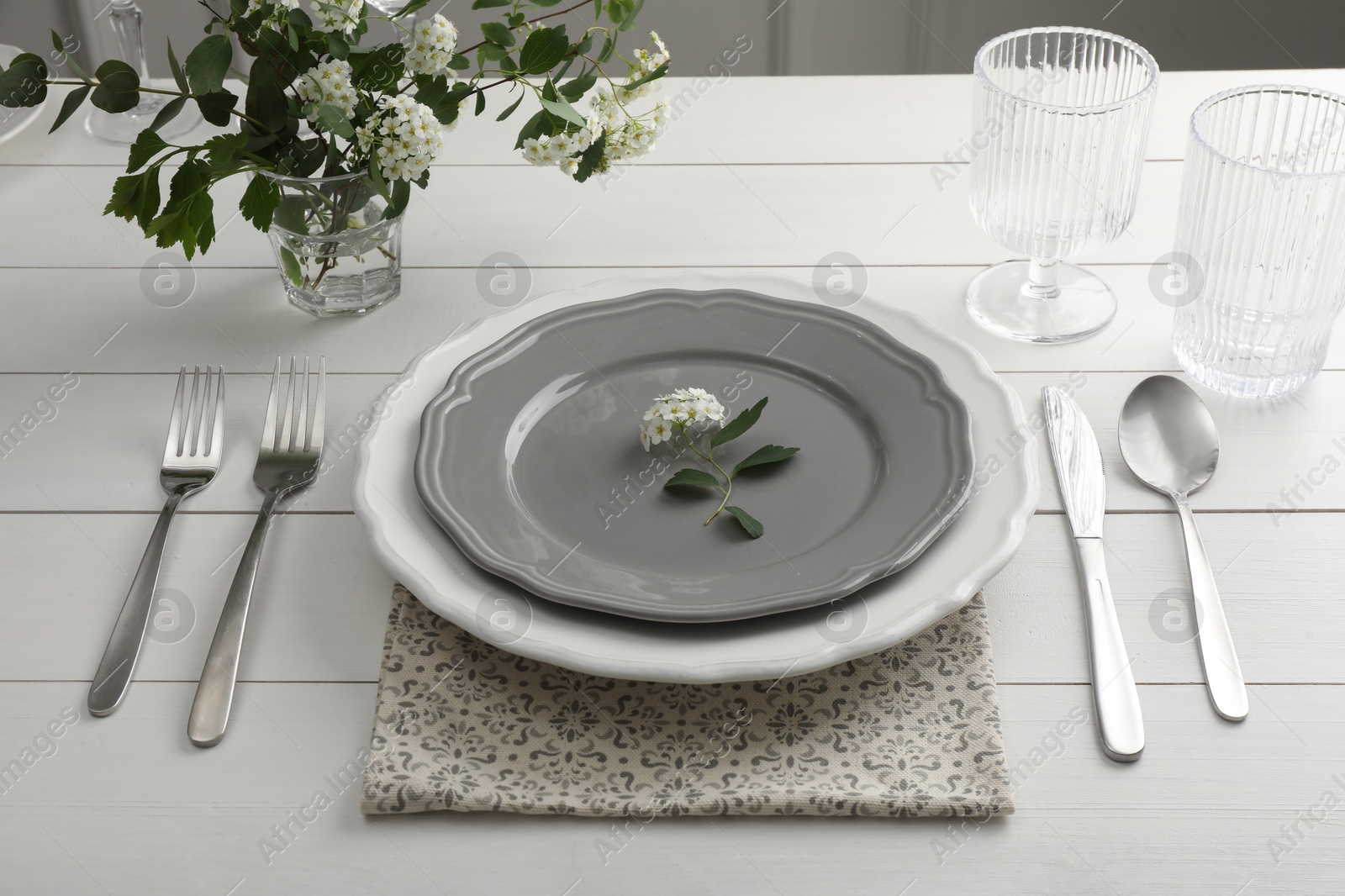 Photo of Stylish setting with cutlery, glasses and plates on white wooden table