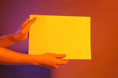 Man holding sheets of paper on color background, closeup and space for text. Mockup for design
