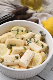 Dish with raw salsify roots, lemon and thyme on white wooden table, closeup