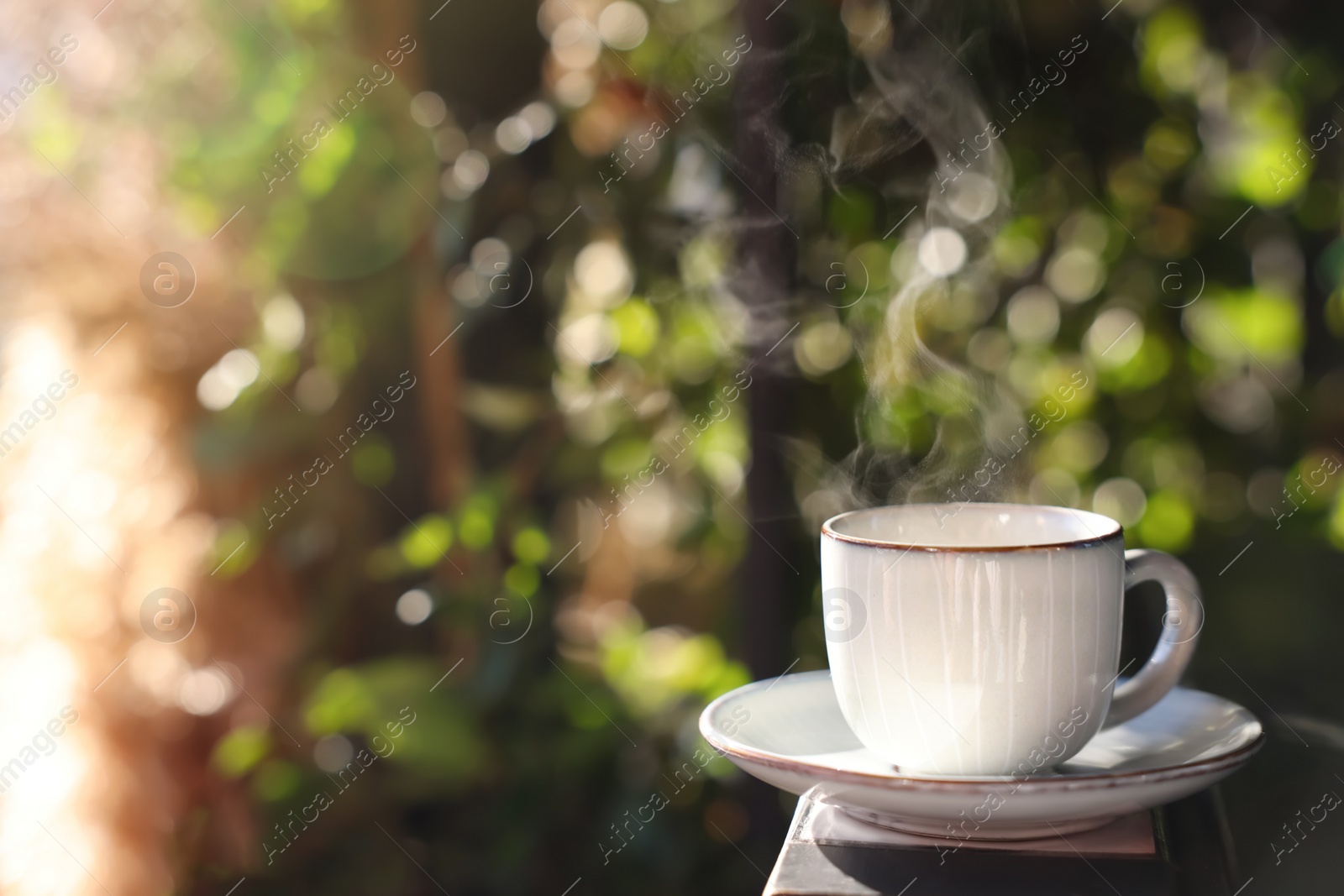 Photo of Cup of hot aromatic coffee on table in outdoor cafe. Space for text