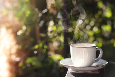 Photo of Cup of hot aromatic coffee on table in outdoor cafe. Space for text