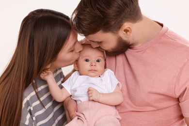 Happy family. Parents kissing their cute baby on light background