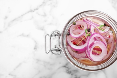 Photo of Jar of pickled onions on marble table, top view. Space for text