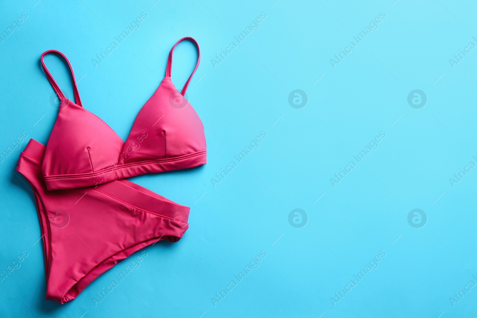 Photo of Beautiful pink bikini on light blue background, top view. Space for text