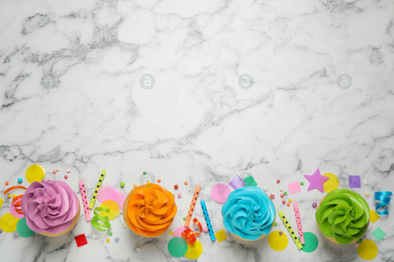 Photo of Colorful birthday cupcakes on marble table, flat lay. Space for text