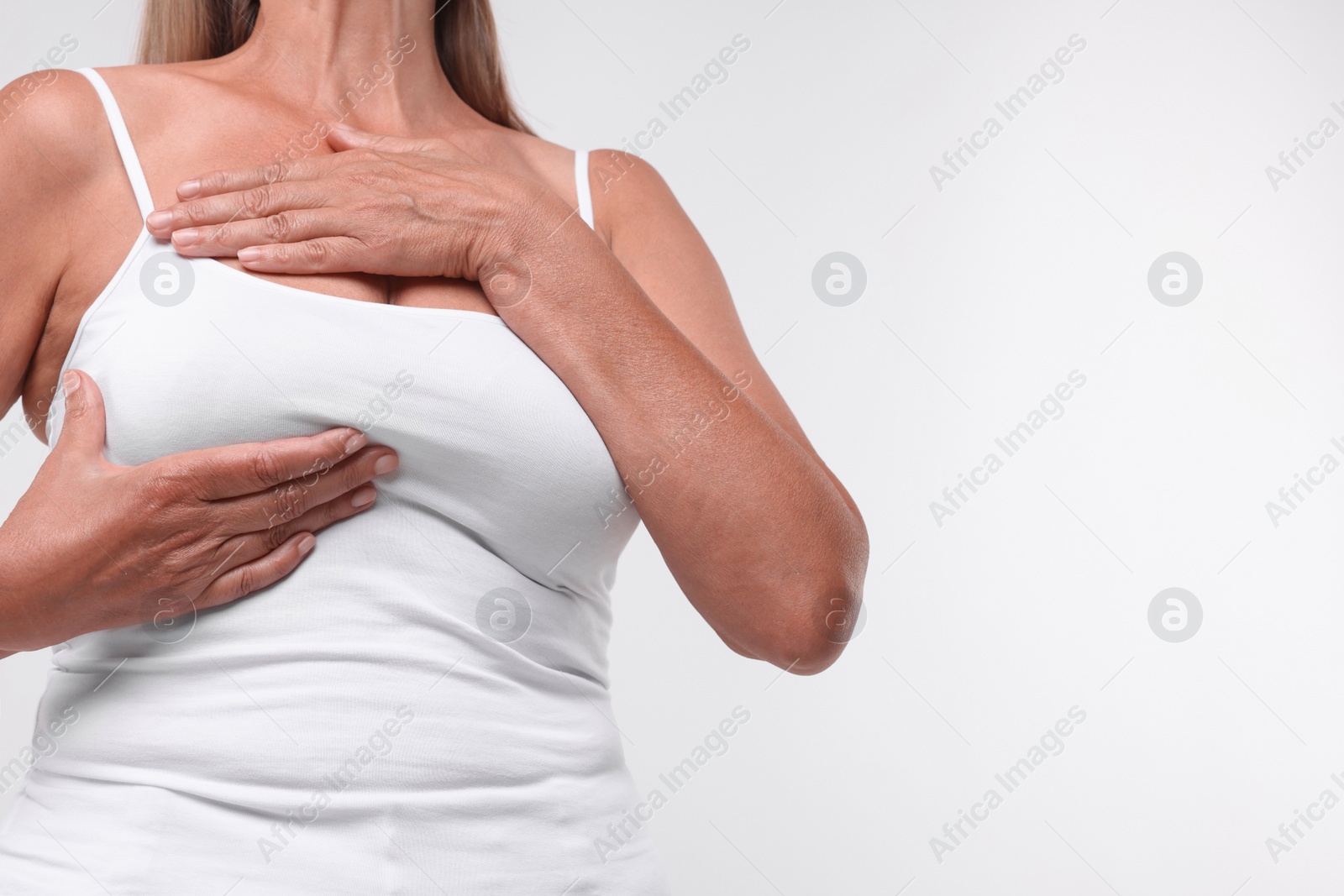 Photo of Woman doing breast self-examination on white background, closeup. Space for text