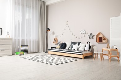 Cute kids room with stylish comfortable floor bed and toys. Montessori interior