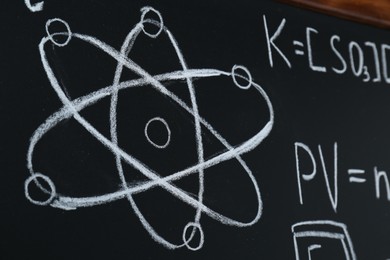 Photo of Different mathematical formulas written with chalk on blackboard, closeup