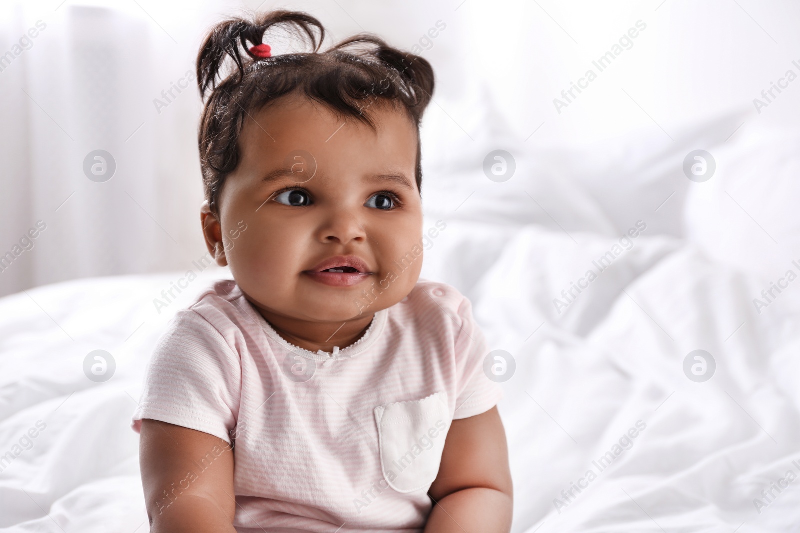 Photo of Cute African American baby on bed at home