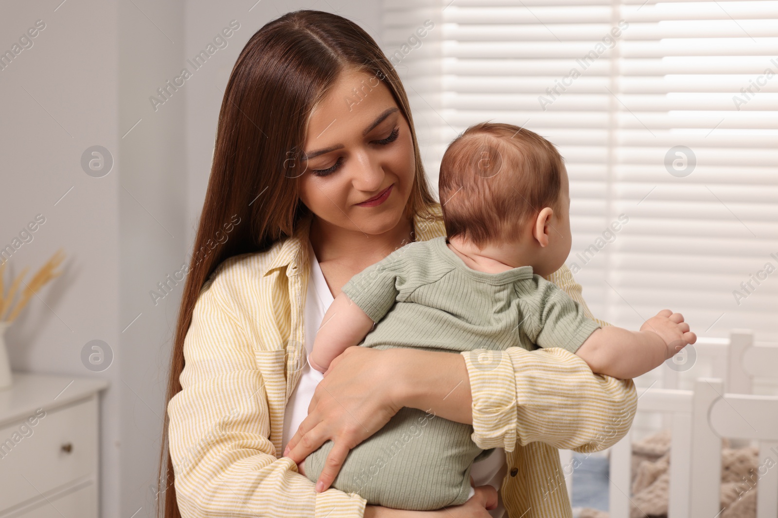 Photo of Mother holding her cute newborn baby in child's room