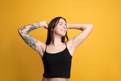 Photo of Beautiful woman with tattoos on arm against yellow background