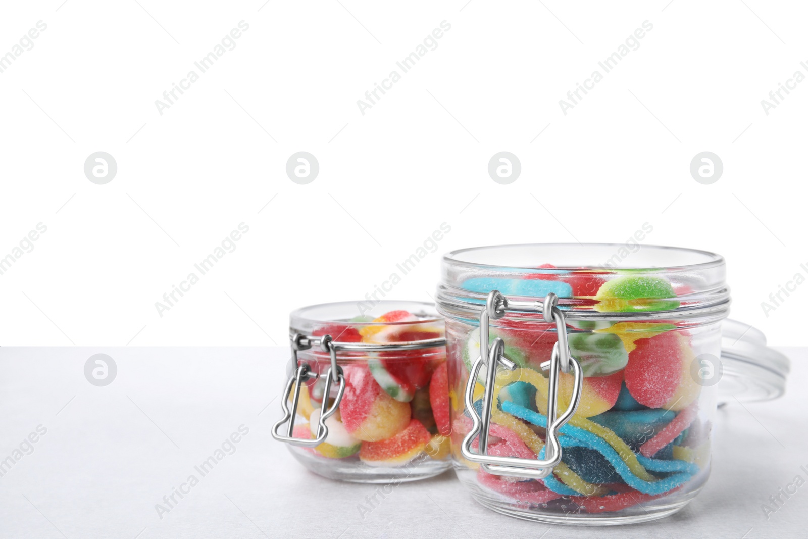 Photo of Tasty jelly candies in jars on light grey table