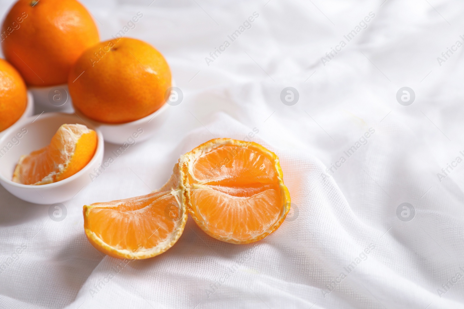 Photo of Fresh ripe tangerines on white cloth. Space for text