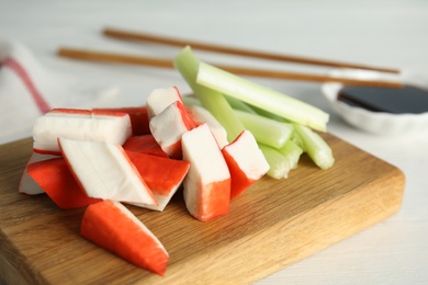 Photo of Fresh crab sticks with celery served on wooden table, closeup