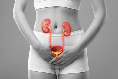 Woman suffering from cystitis on light grey background, closeup. Illustration of urinary system