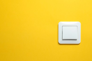 Photo of Modern plastic light switch on orange background. Space for text
