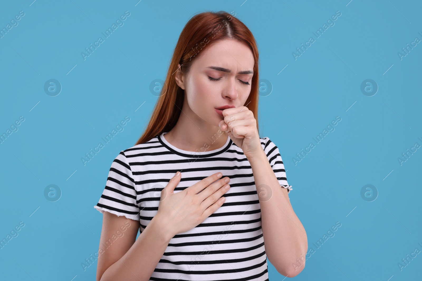 Photo of Woman coughing on light blue background. Cold symptoms