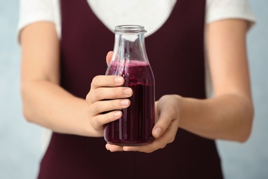 Photo of Woman with bottle of beet smoothie on light background, closeup