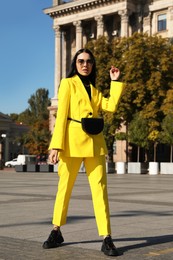 Beautiful young woman with stylish waist bag on city street