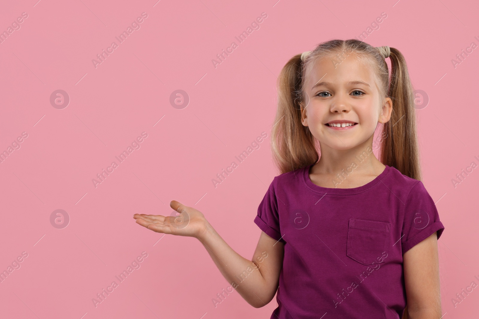 Photo of Special promotion. Little girl showing something on pink background. Space for text