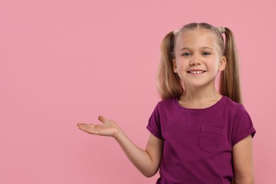 Special promotion. Little girl showing something on pink background. Space for text