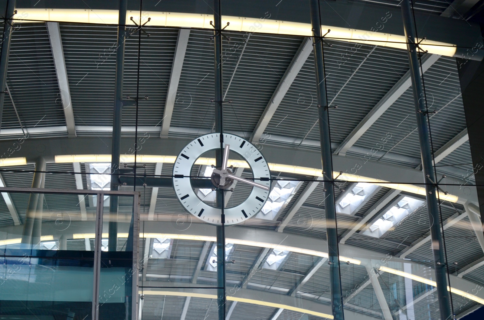 Photo of Beautiful modern clock hanging on big glass indoors