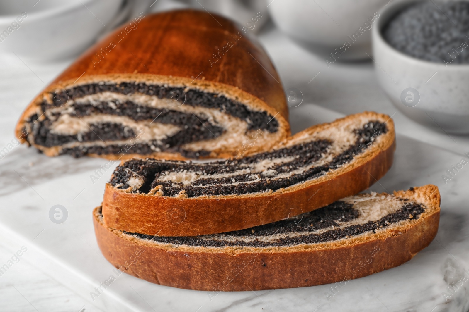 Photo of Cut tasty sweet bun with poppy seeds on gray table