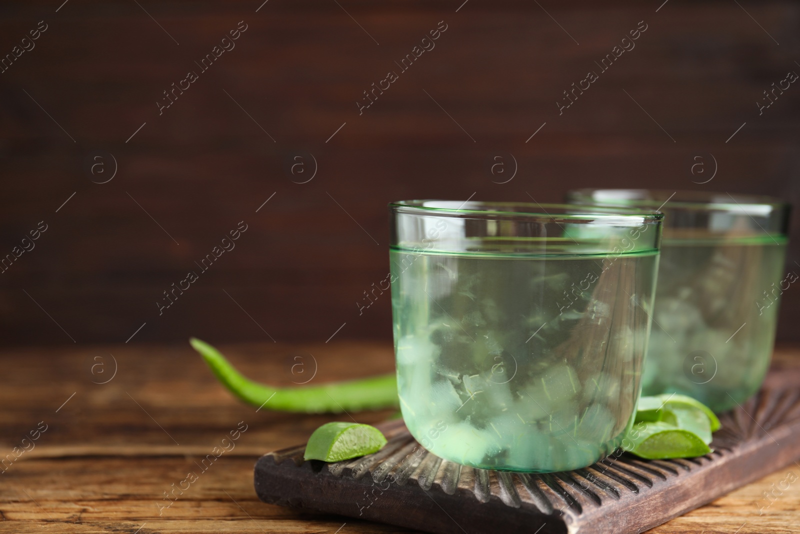 Photo of Fresh aloe drink in glasses on wooden table, closeup. Space for text