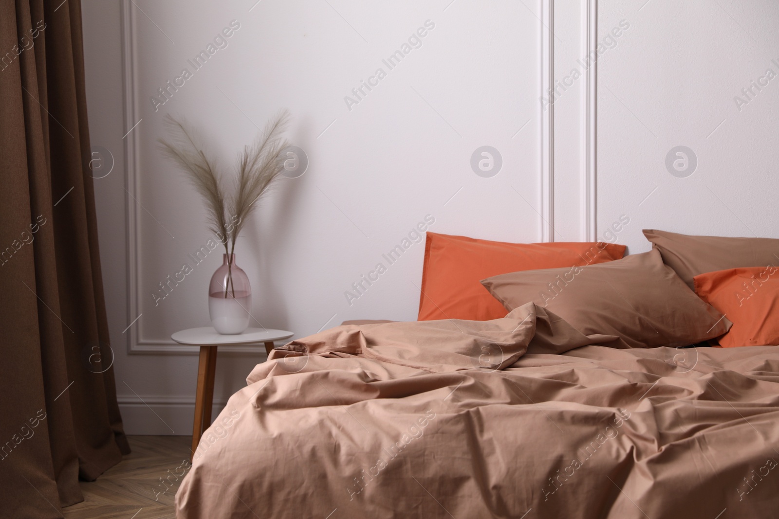 Photo of Bed with orange and brown linens in stylish room