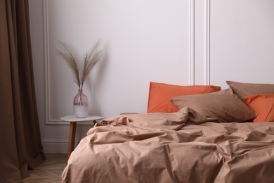 Photo of Bed with orange and brown linens in stylish room